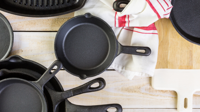 Variety of cast iron pans laid out on table with kitchen towel.