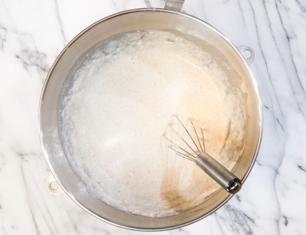 Pancake batter in silver mixing bowl with whisk. 