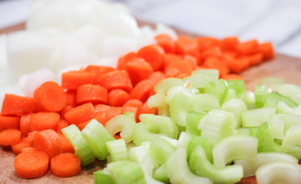 Diced celery, carrots, and onions on cutting board.