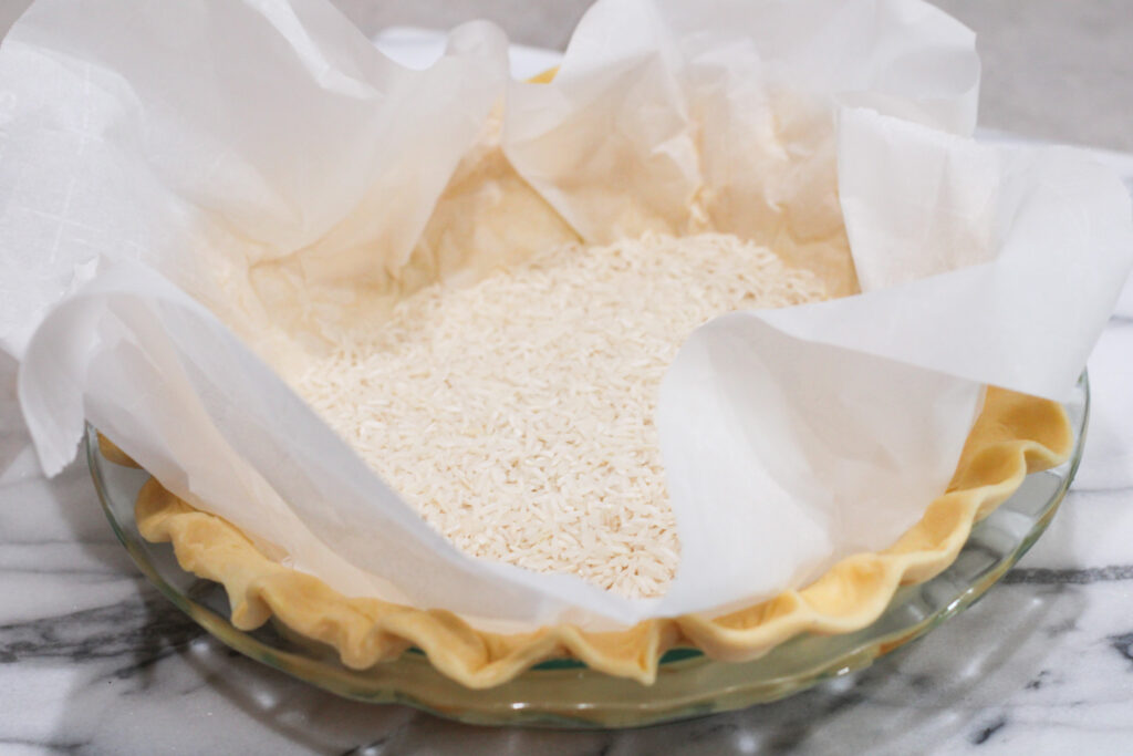 Pie crust with rice on parchment paper to blind bake. 