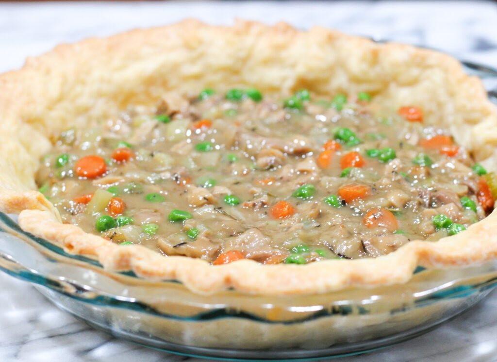 Pie shell with pot pie ingredients inside. 