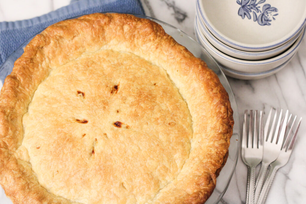 Pie with forks and bowls on table. 