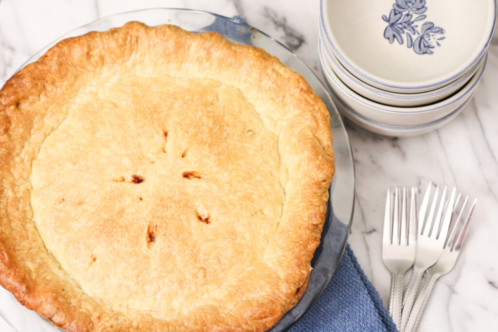 Cooked Pie with bowls, blue napkin, and forks. 