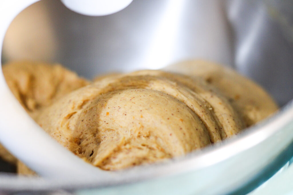 Close up of Pumpkin Cinnamon Roll Dough on dough hook in mixing bowl
