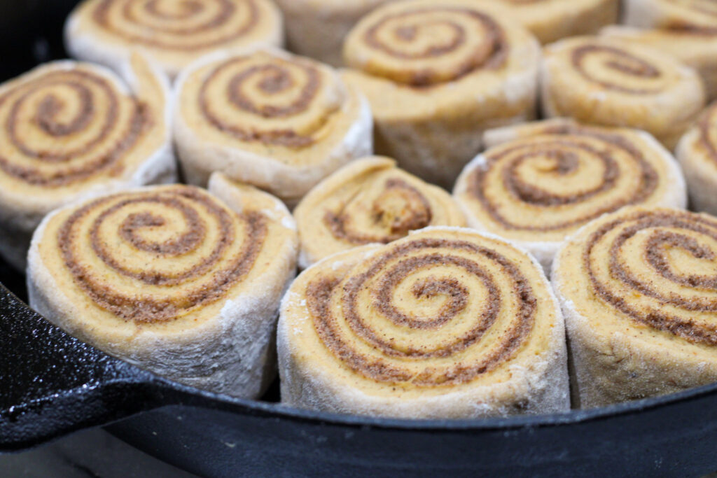 Unbaked Pumpkin Spice Cinnamon Rolls in Cast Iron Pan.