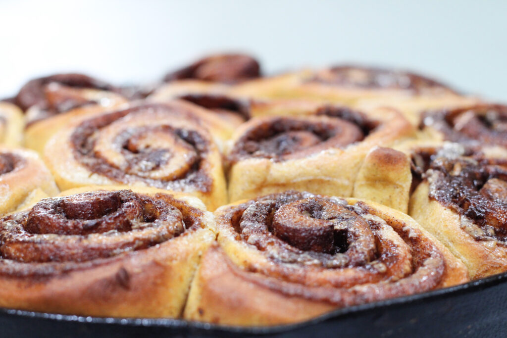 Baked, but unfrosted Pumpkin Spice Cinnamon Rolls in Cast Iron Pan.