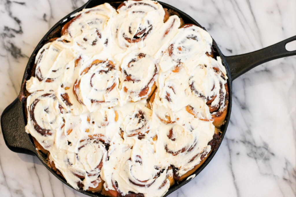 Baked and frosted Pumpkin Spice Cinnamon Rolls in Cast Iron Pan.