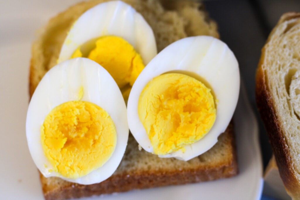 Boiled eggs sliced on piece of bread.