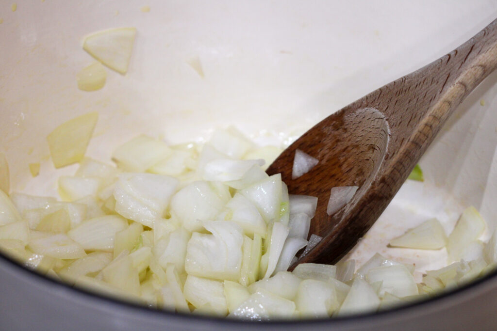 Pot with onions cooking and wooden spoon.