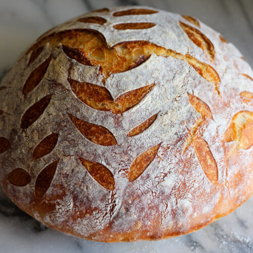 Baked artisan sourdough bread loaf with leaf pattern.