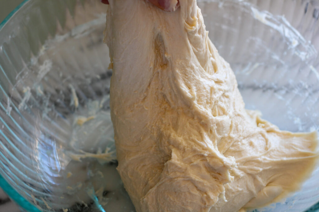 Stretching sourdough bread dough in glass bowl.