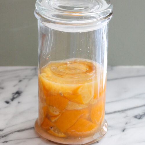 Lemons submerged in juice in a glass jar.