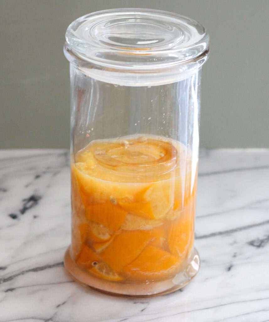 Lemons submerged in juice in a glass jar.