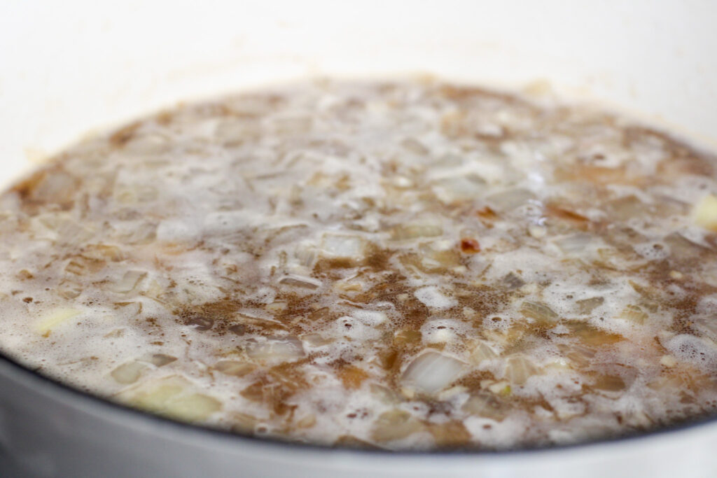 Potato, beer, cheese soup ingredients cooking in pot.