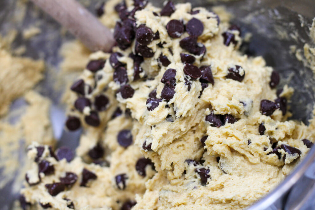 Sourdough chocolate chip cookie dough in bowl with spatula.