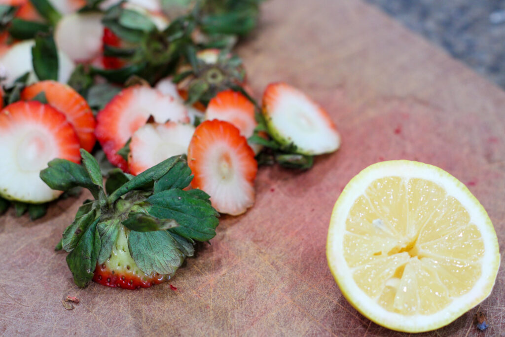 strawberry tops and half of lemon on cutting board
