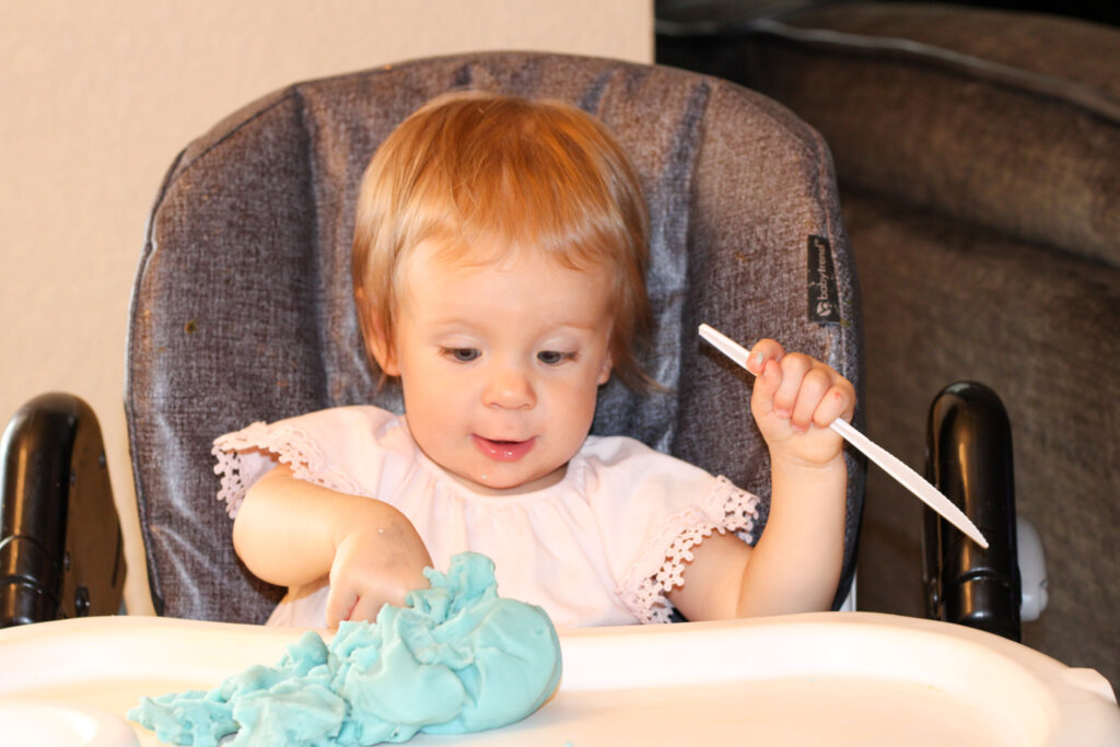 Baby playing with blue homemade play dough.