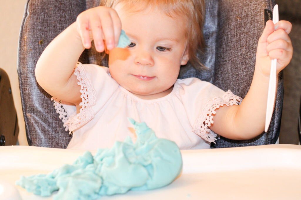 Baby playing with blue homemade play dough.