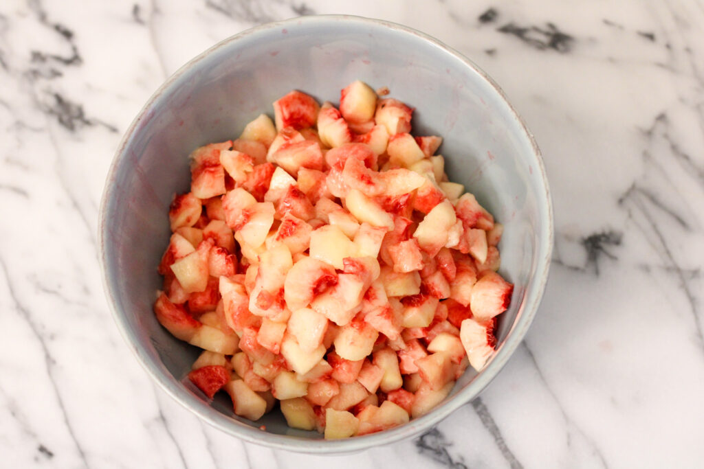 Blue bowl of chopped peaches.