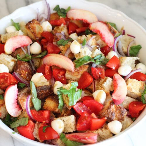 White bowl with peach panzanella salad.