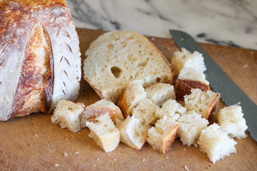 Cubed sourdough bread on cutting board.