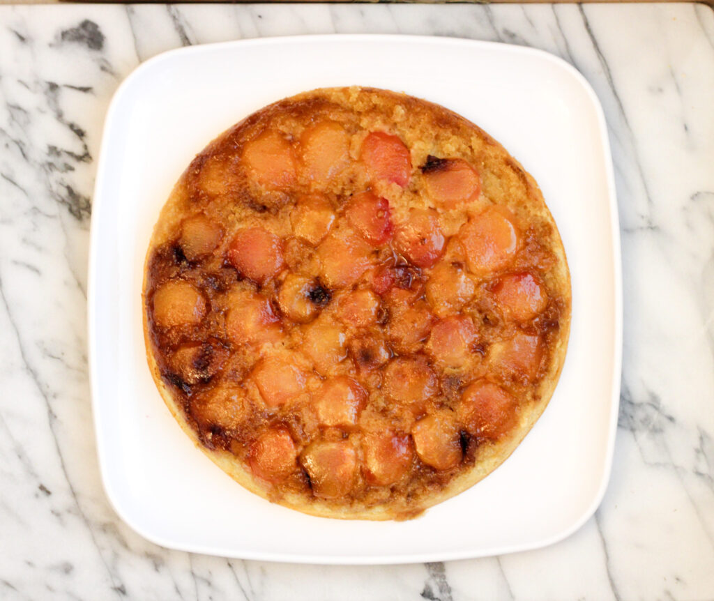 Whole peach upside down cake on square platter.