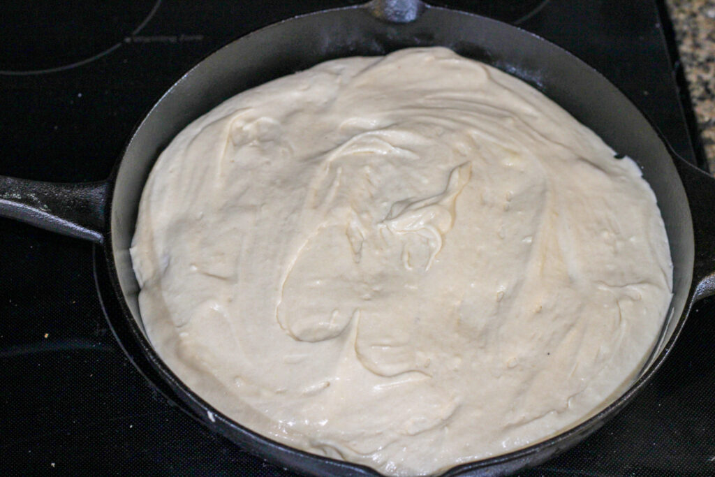 Uncooked peach upside down cake in cast iron pan.