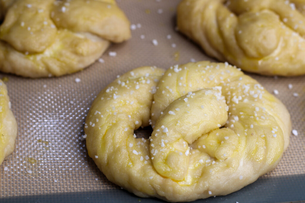 Unbaked sourdough soft pretzels on baking sheet.