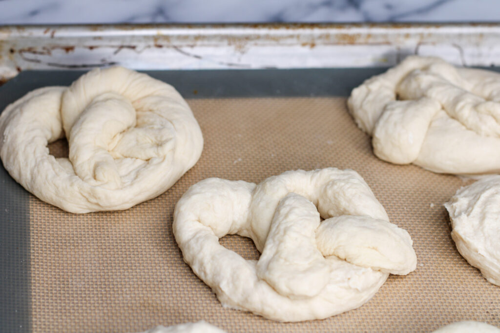 Unbaked sourdough soft pretzels on baking sheet.