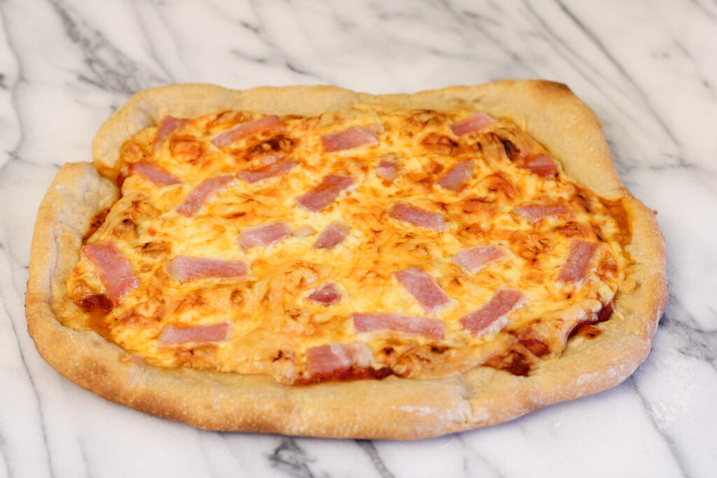 Homemade pizza baked and resting on marble countertop. 