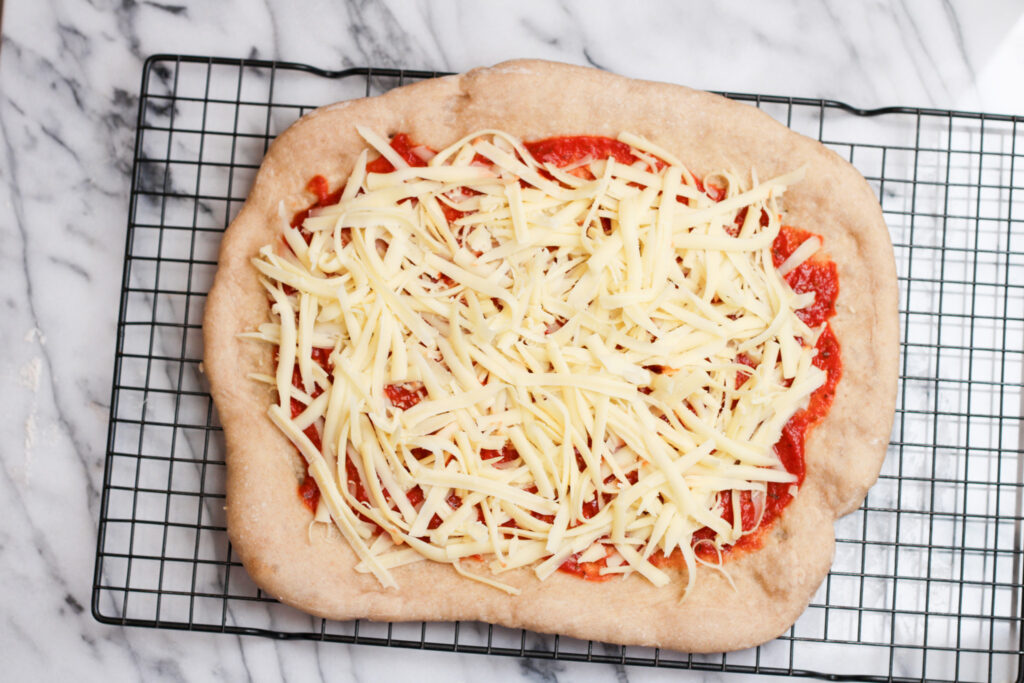 Homemade frozen pizza with un-melted cheese on cooling rack. 