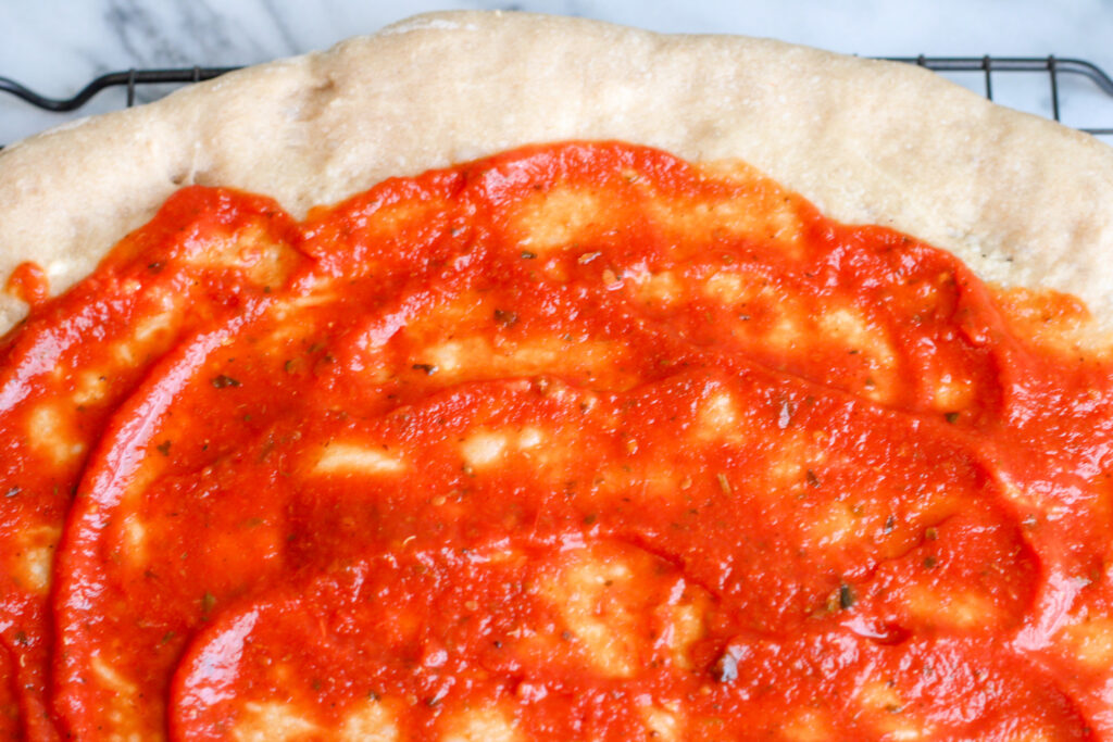 Close up of pizza crust with sauce. 