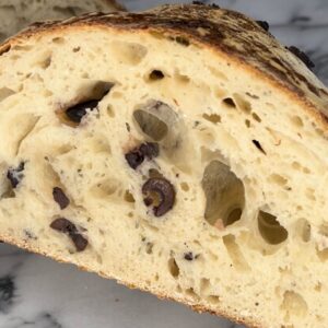 Sourdough olive and rosemary bread loaf sliced in half.