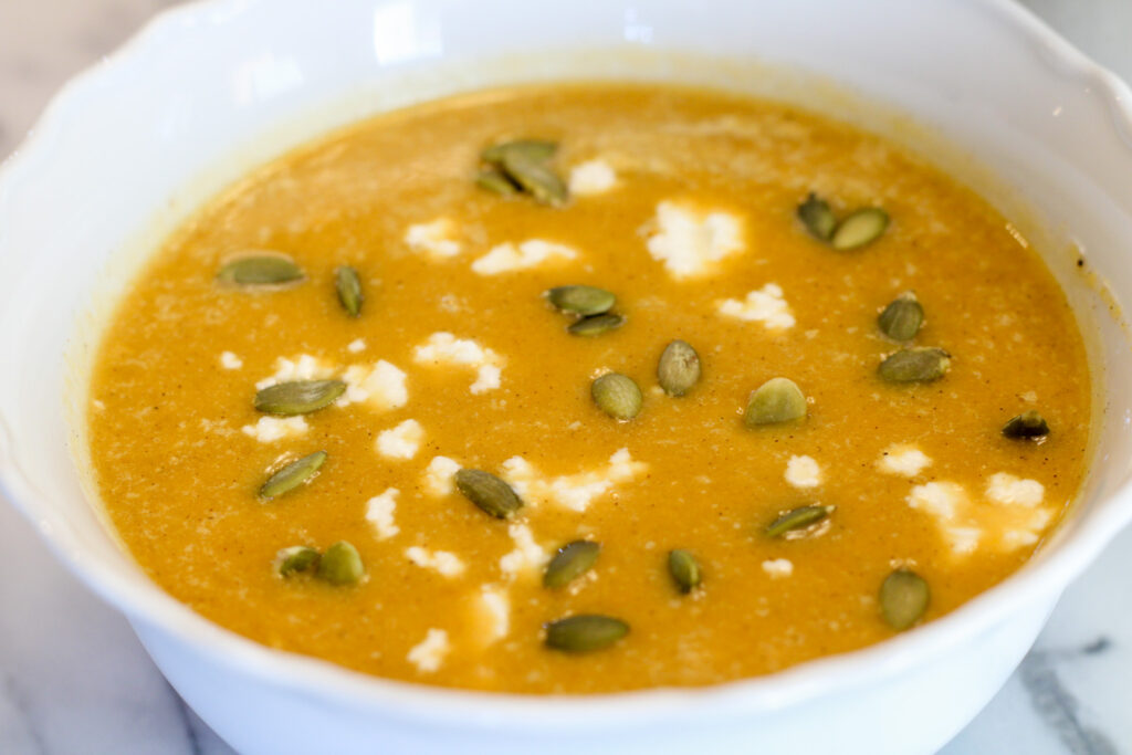 Bowl of butternut squash soup with pumpkin seeds and goat cheese.