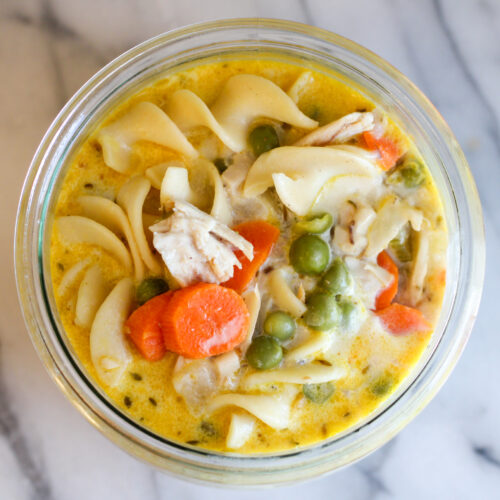 Bowl of creamy chicken noodle soup on marble countertop