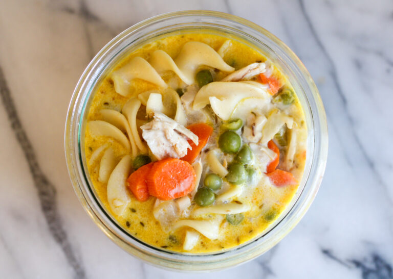 Bowl of creamy chicken noodle soup on marble countertop