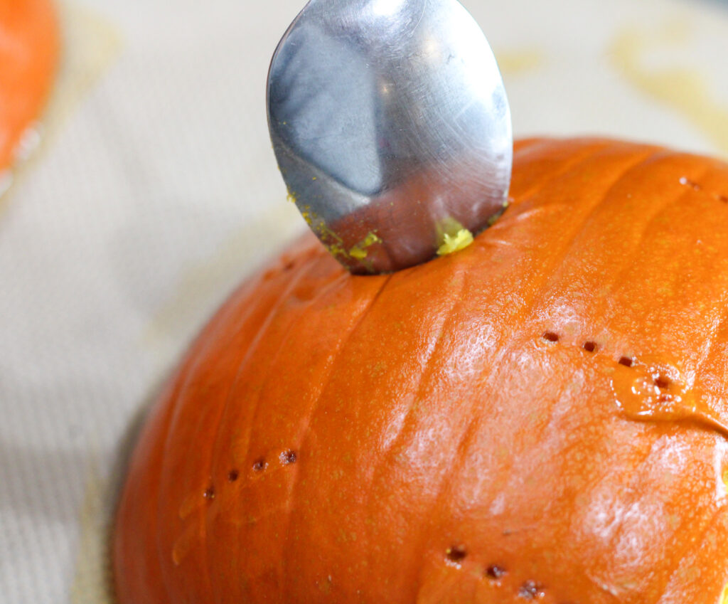 Spoon poking into roasted pumpkin skin.