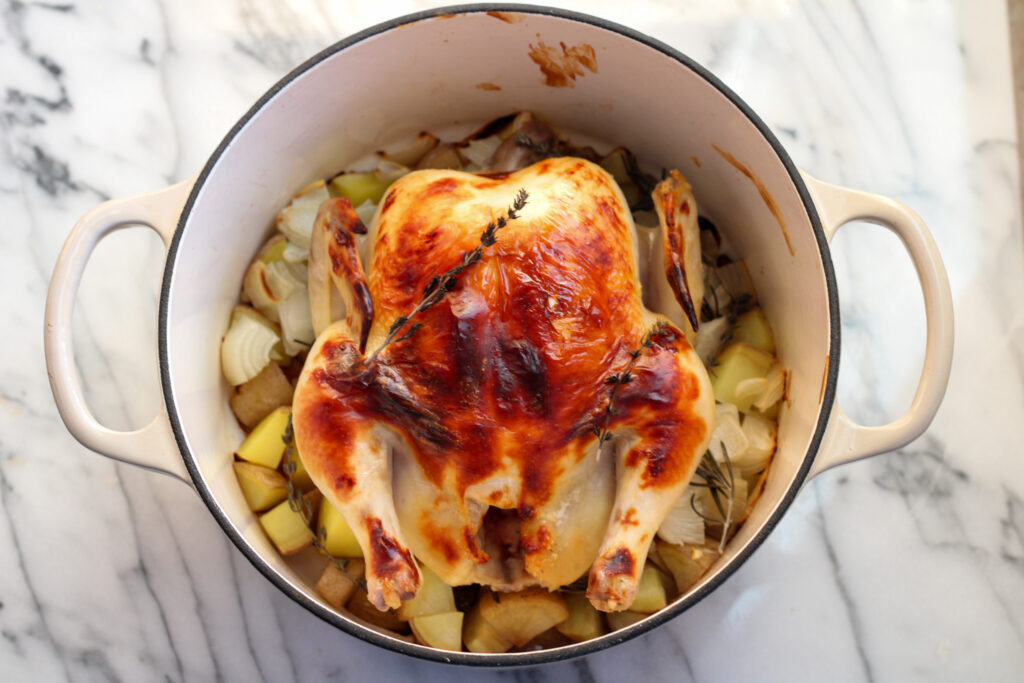 Roasted Chicken in dutch oven with potatoes and onions.