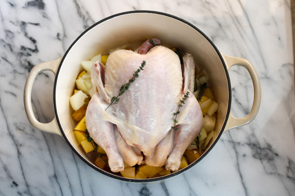 Raw Chicken in dutch oven with potatoes and onions.