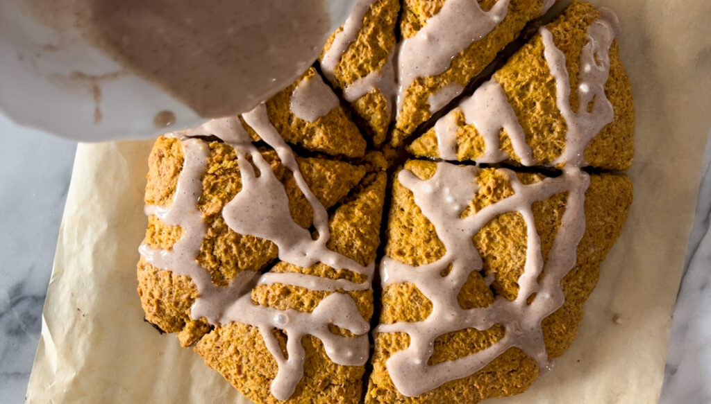 Drizzling spiced glaze onto - pumpkin scones. 