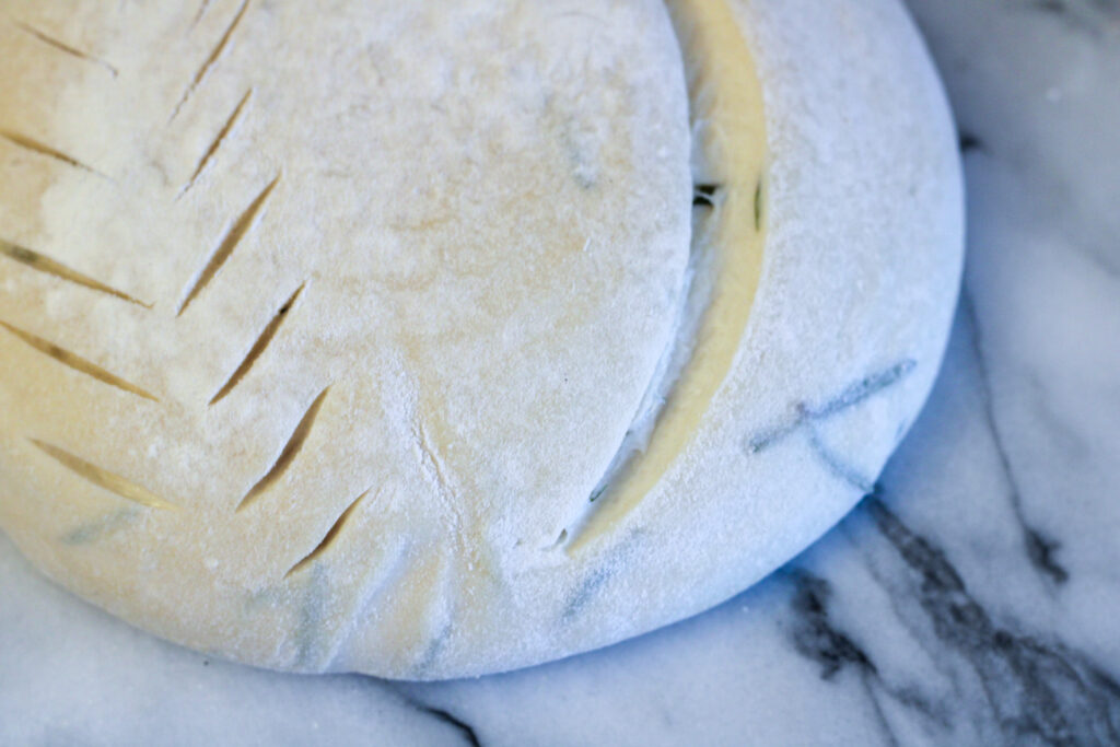 Scored sourdough herb bread dough.