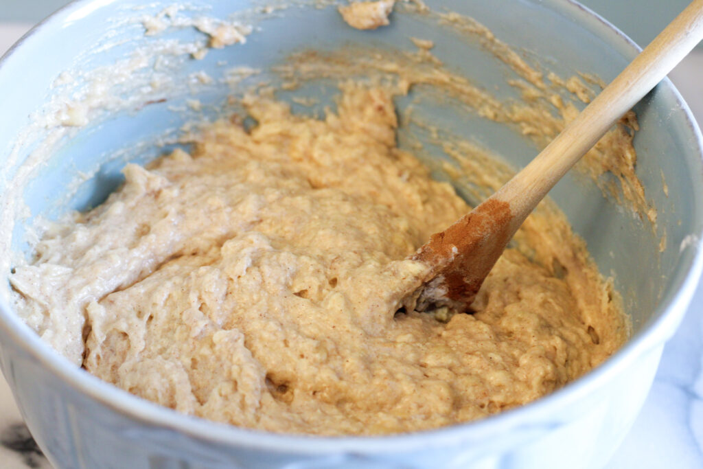Bowl of sourdough banana bread batter with wooden spoon. 