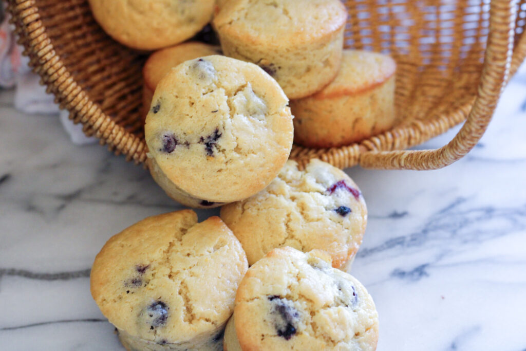 Blueberry muffins spilling out of woven basket. 