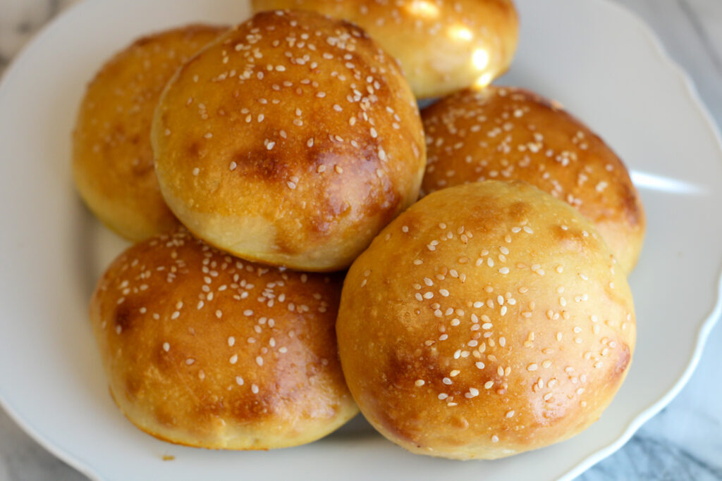 Stack of unsliced burger buns on plate.
