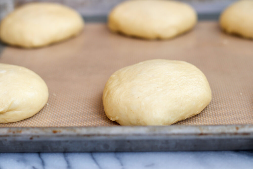Shaped bun dough on baking sheet.